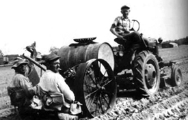 Ross Joseph Nichols and Louis Vann transplant tobacoo on the Nichols farm in the Roanoke-Chowan area of North Carolina.  The planter was originally pulled by mules, but the mules have been replaced by the tractor.  This one is driven by Fred Nichols.  Photo by the Nichols family.