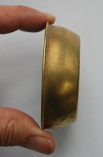 Pictured is a small brass object.  This household item is three inches in diameter, and it is one inch deep.