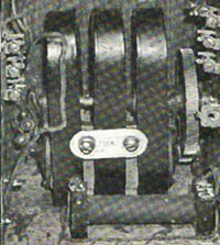 This three part iron object is roughly six inches tall and four inches wide.  The wheel on the right is brass and has small teeth around its perimeter.