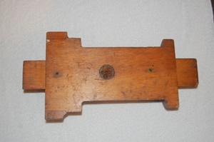 On the flat side are two small metal-lined holes and a circular metal disk 11/2 inches in diameter with five screws in it.